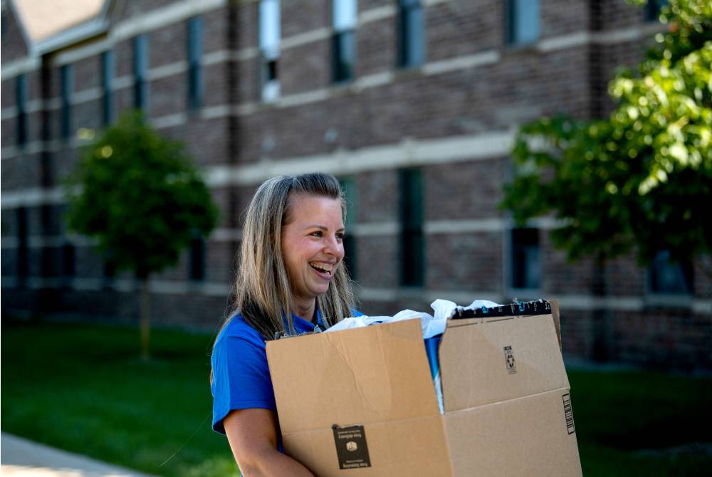 An Alumna carrying a student's box.